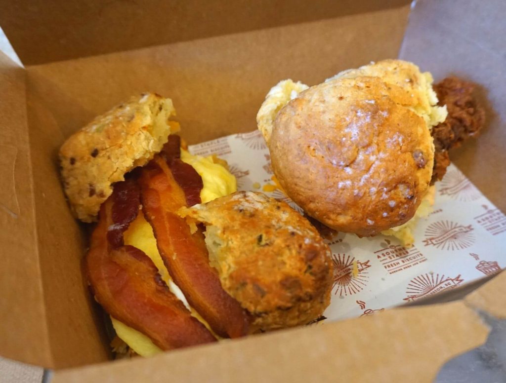 Bacon, egg, and cheese sandwich on two cheese and chive biscuits and a fried chicken sandwich on a butter biscuit