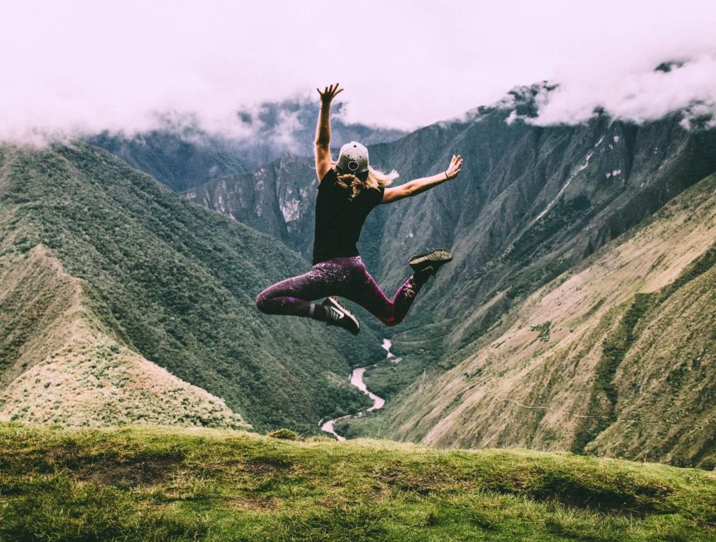 girl jumping with mountains in the background