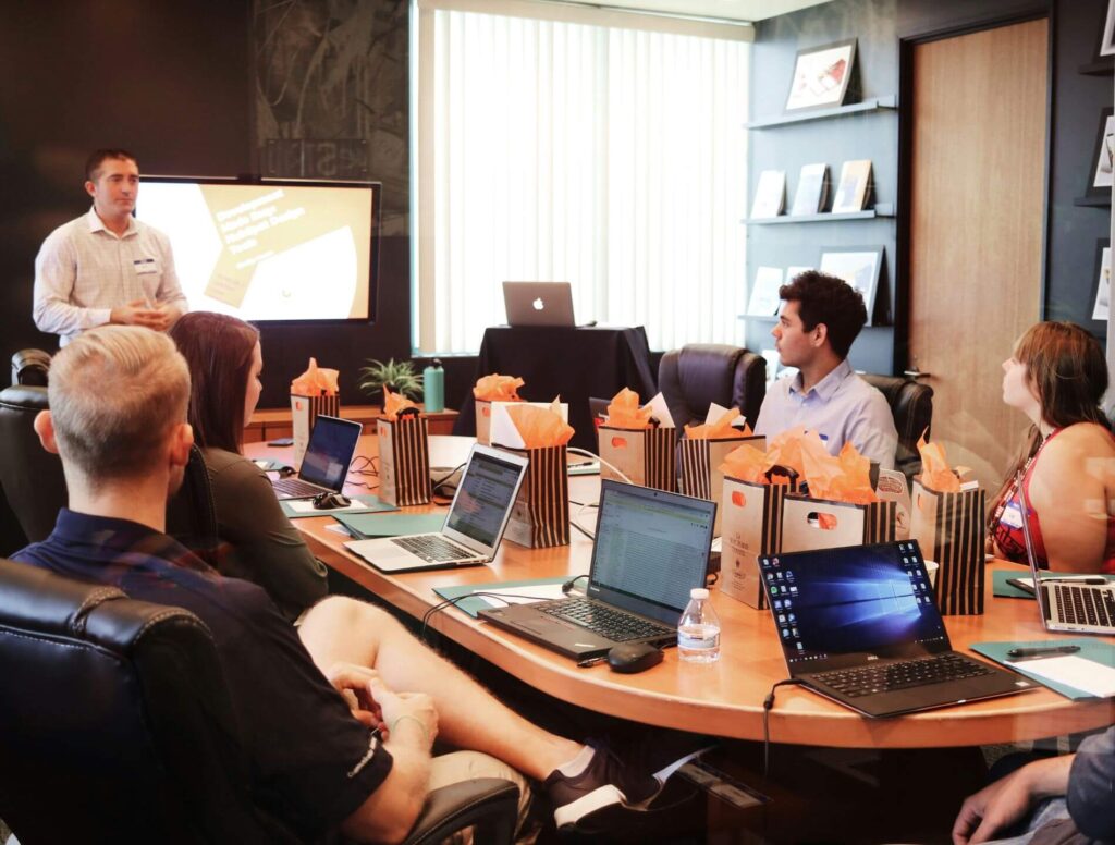 people sitting around a desk with their laptops open