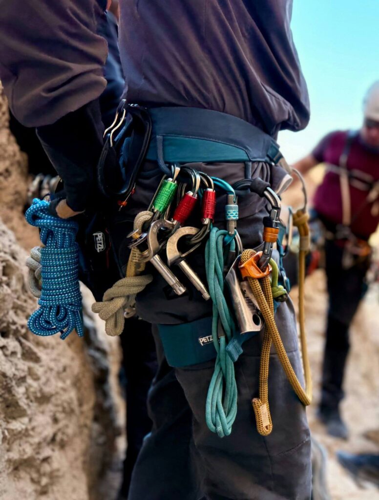 male climber with ropes and carabiners hanging from his waist